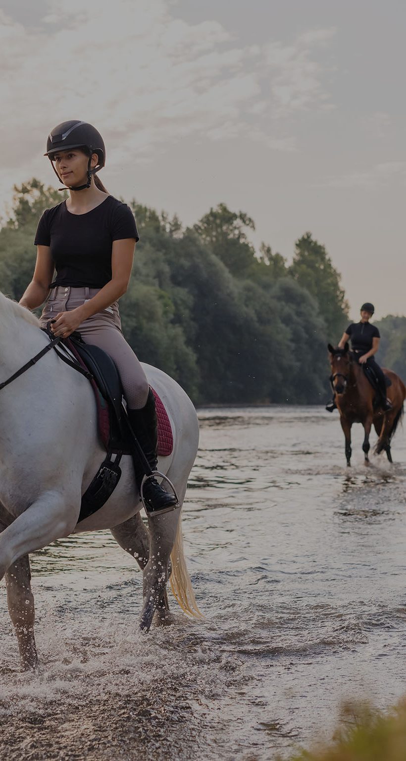 Three female riders crossing the river by riding horses